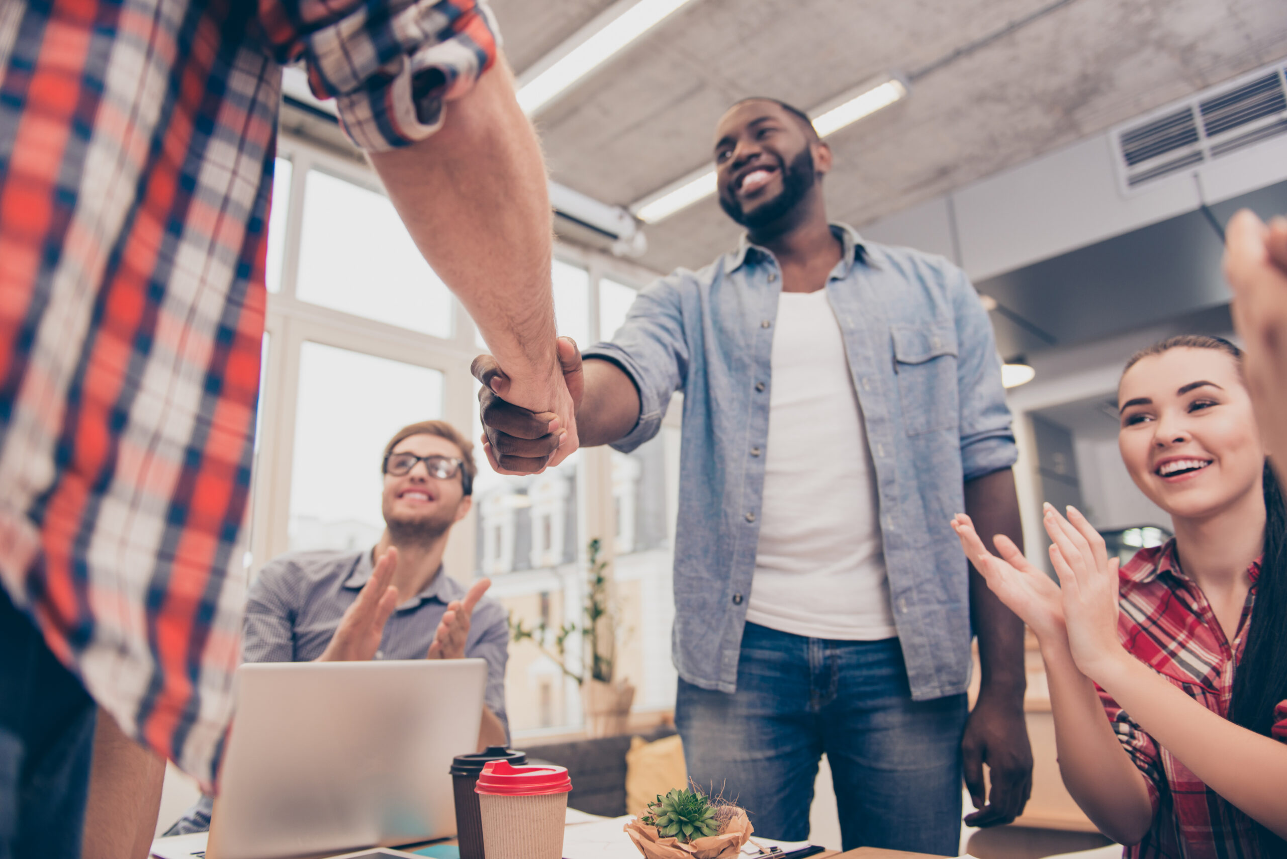 Contact Us two successful young businesspeople shaking hands in office